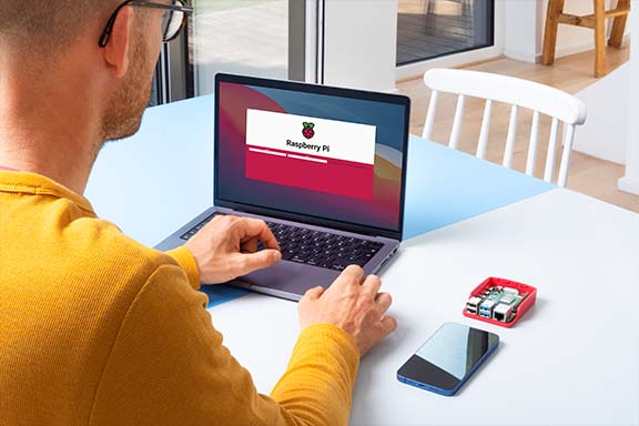 Osoba siedząca przy stole z laptopem i Raspberry Pi chcąca zainstalować Homebridge