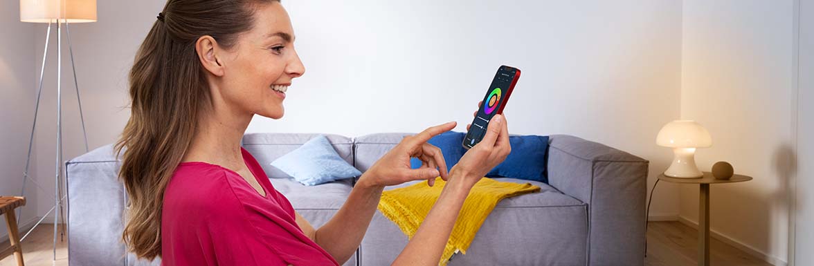 Kobieta obsługująca aplikację Smart Home na swoim smartfonie